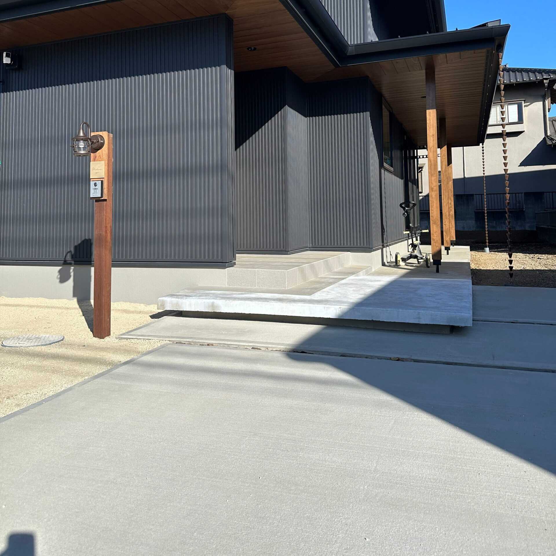 黒い外壁の住宅玄関前に土間コンクリートを施工した様子
