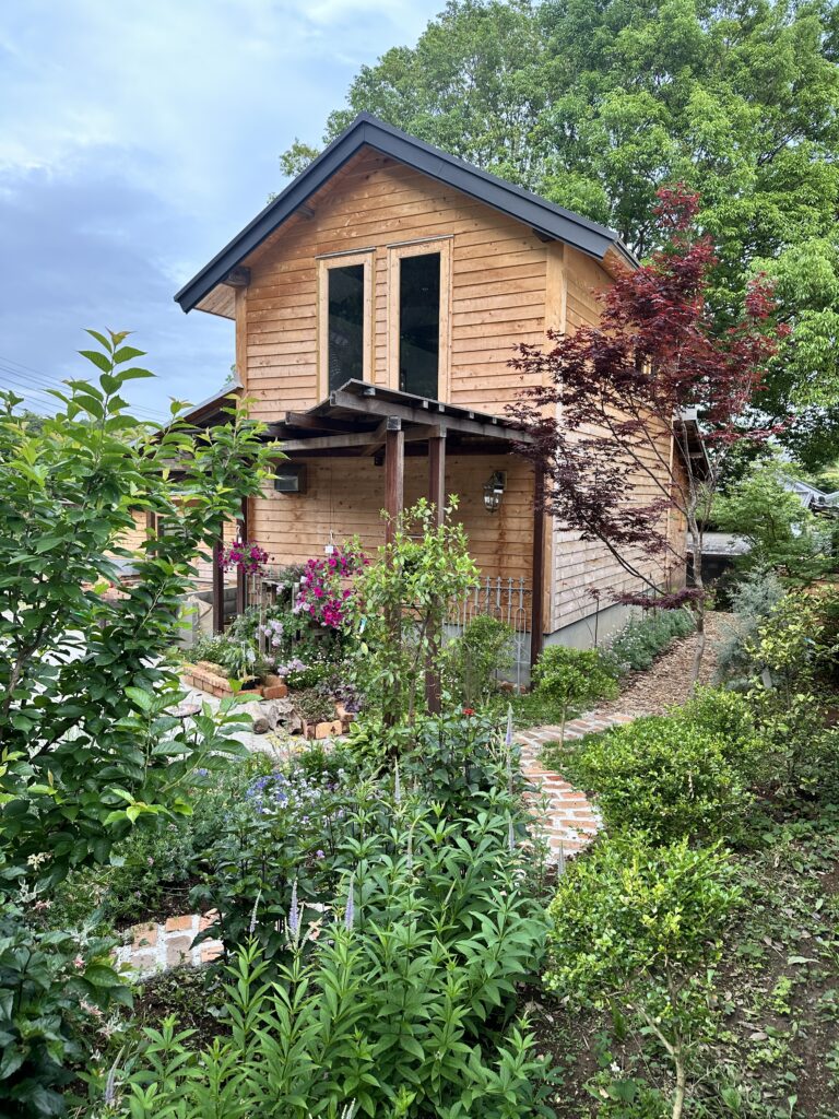 木造の建物とレンガ調の小道、草花に囲まれた自社ガーデンの様子