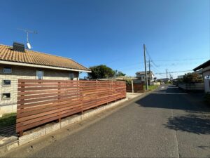 施工後：道路沿いに設置されたウリン材の長い木製目隠しフェンス